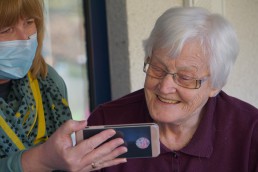 Blonde woman shows older woman a Facetime call.