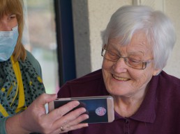 Blonde woman shows older woman a Facetime call.