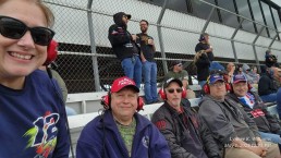 Group sitting in stands at NASCAR race.