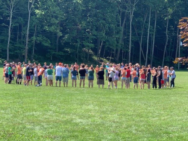Group of teens in grass at camp.