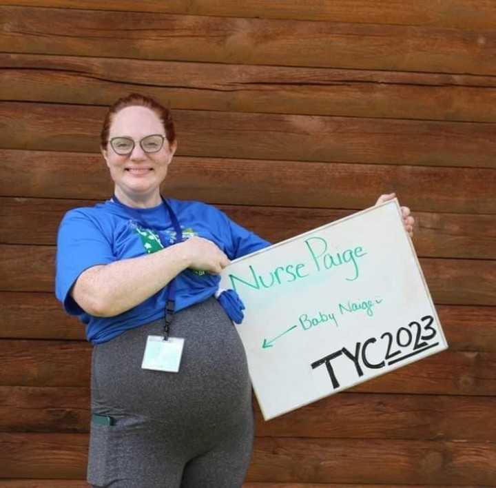 Pregnant woman holding sign that says 